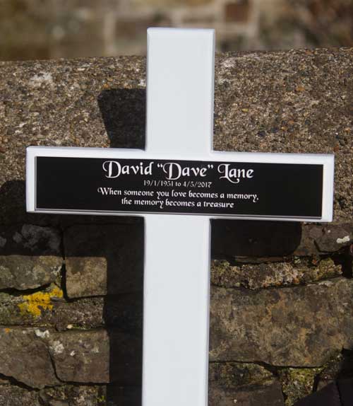 Black acrylic plaque with white text on a white painted oak cross