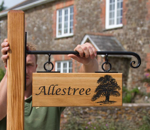 Carved oak sign with posts and wrought iron hanging bracket