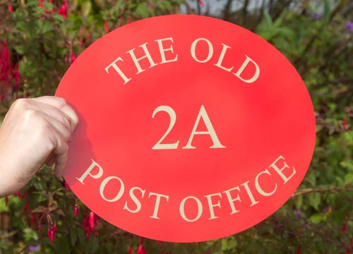 Red oval home sign with gold lettering