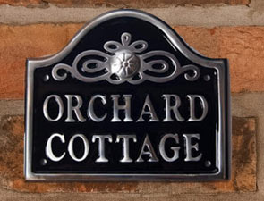 Cast aluminium sign with arch top and motif.