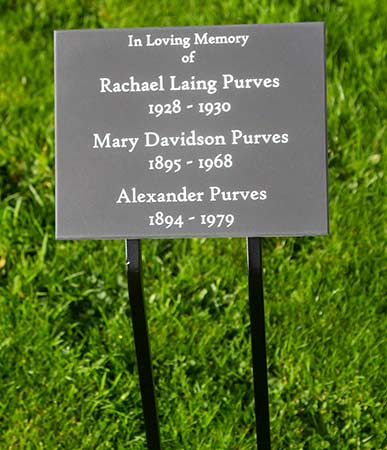 Slate memorial on wrought iron plate with tree stakes.