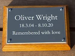 Acrylic laminate memorial plaque mounted on a wooden backing board.