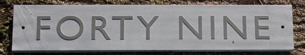 Slate house sign with raised letters. Font Gill Sans with extra spacing