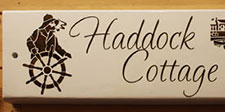 Painted cottage sign with the cottage name and images laser etched