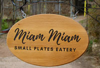 Hanging oval wood sign on a bracket.