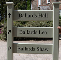 Painted wooden ladder sign with arroes on the post.