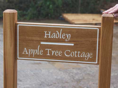 Oak sign morticed into posts with white painted letters.
